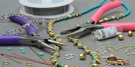 A colorful jewelry-making scene with pliers, wire, beads, and clasps on a gray surface. Evokes creativity and craftsmanship.