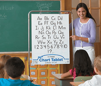 Teacher using a Chart Tablet with alphabet and numbers in front of a classroom.
